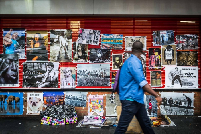 Muro pieno di poster con passante che li guarda