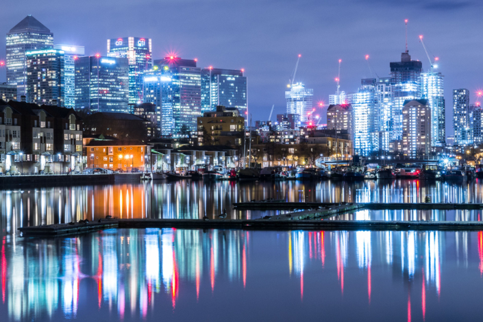 Palazzi di Londra visti di sera con uno specchio d'acqua che riflette tutte le luci
